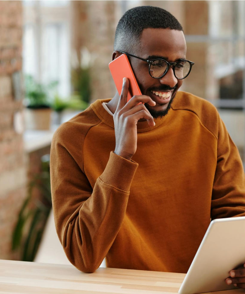 A man sitting at a table talking on a cell phone.